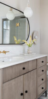Bathroom vanity with wood cabinetry, wall mirror, and pendant light
