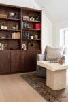 Modern mountain homes seating area with built-in wood bookcase, lounge chair, stone coffee table, and patterned rug