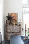 Dining room with cerused wood cabinet, vintage pottery, and colorful art in a contemporary Hudson Valley mountain home.