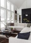 Modern mountain homes living room area with sectional sofa, decorative pillows, greenery, round coffee table, and large windows