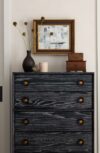 Vignette with dark cerused wood dresser, framed artwork, vintage decor, and plastered wall