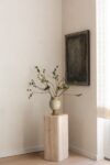 Modern mountain homes corner with wood pedestal, ceramic vase, branch arrangement, framed wall art, and soft window light