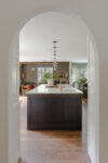 Arched doorway leading to kitchen with wood cabinets, marble counters and a breakfast nook in a Tudor Revival Westfield home
