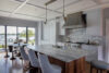 Kitchen with custom teak countertops, curved cabinetry, sea glass tile backsplash, and marine-grade finishes in a Westchester coastal estate.