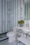 Light blue and white pinstripe washroom inspired by nautical design elements.