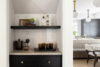 Built-in beverage station with dark cabinetry, open shelving, tiled backsplash, and glassware storage