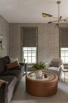 Home office lounge with sofa, accent chairs, round coffee table, windows, and statement ceiling light