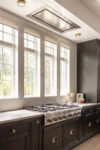 Kitchen with dark cabinetry, range, tall windows, and ceiling light