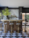Luxury home bar with fluted brass counter stools, checkered floor, marble back splash and ocean views in Westchester coastal luxury estate.