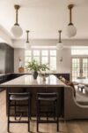 Contemporary kitchen with large island, dark cabinetry, marble countertops, and pendant lighting