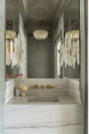 Powder room with marble sink, custom millwork, and soft patterned walls in a transitional Short Hills family home.