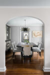 Arched doorway in a Westfield, New Jersey home leading into a dining room with grasscloth walls in warm grey, crown moldings, and transitional interior design details.