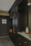 Mudroom with dark wood cabinetry and marble counter reflecting English charm and modern comfort.