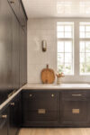 Contemporary residence Short Hills kitchen corner with dark cabinetry, tall windows, tile wall, and warm wood accent