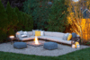Backyard in Westfield New Jersey featuring a large outdoor sofa, fire pit, and cottage-style architecture.