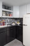 Basement kitchen in a modern Westfield ranch with black and white cabinetry, Smeg refrigerator, and minimalist backsplash.