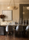 Luxury whole house renovation NJ dining room with long table, upholstered chairs, dual pendant light, wall mirror, artwork, and styled sideboard above a warm-toned cabinetry unit