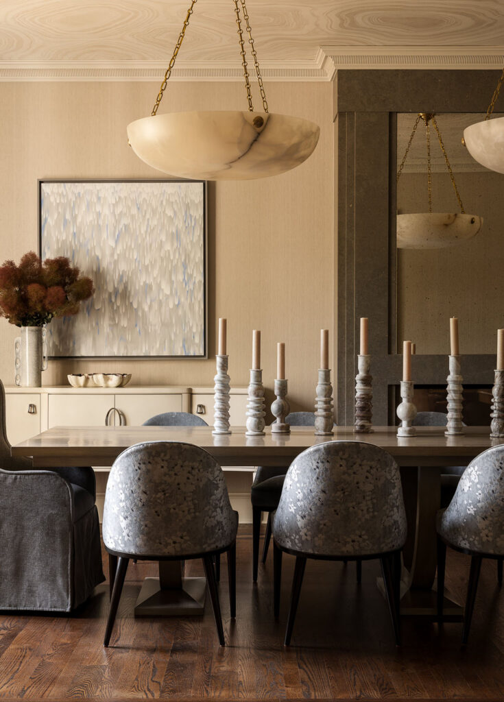 Luxury whole house renovation NJ dining room with long table, upholstered chairs, dual pendant light, wall mirror, artwork, and styled sideboard above a warm-toned cabinetry unit