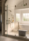 Bathroom with glass shower, freestanding tub, large windows, wall-mounted fixtures, and light stone surfaces
