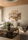 Living room seating area with pendant lighting, wood coffee table, sectional sofa, abstract wall art, greenery, wood ceiling and marble side table