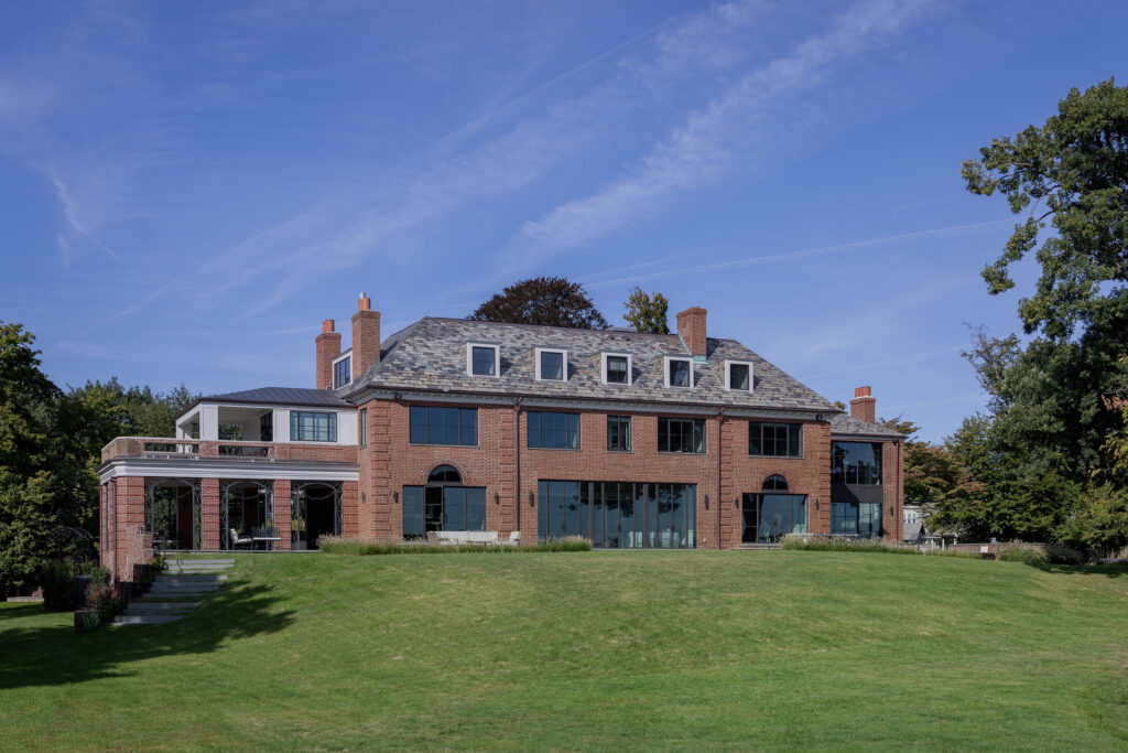 Back elevation of 1930s coastal estate in Larchmont with terraces overlooking Long Island Sound.