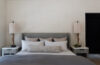 Luxury bedroom with gray upholstered bed, textured bedding, matching nightstands, and decorative table lamps