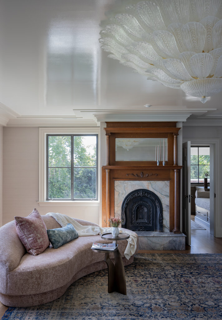 Elegant living room with carved wood fireplace mantel, curved sofa, antique rug, and custom millwork details