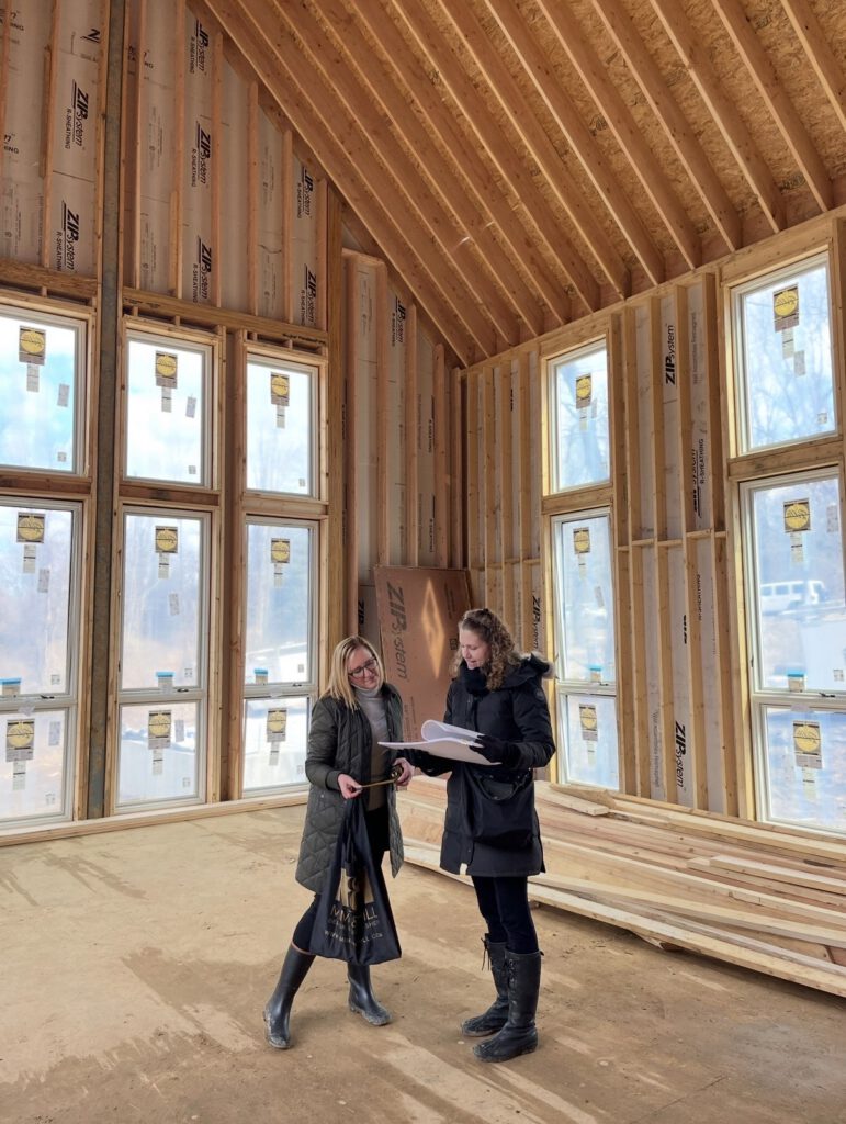 Interior construction site with exposed framing, windows, and architectural plans during home renovation