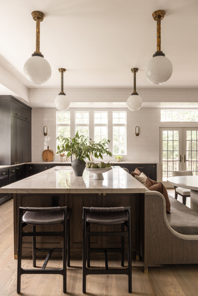 Rosenblatt Residence kitchen with dark cabinetry, marble island, pendant lighting, and built-in seating