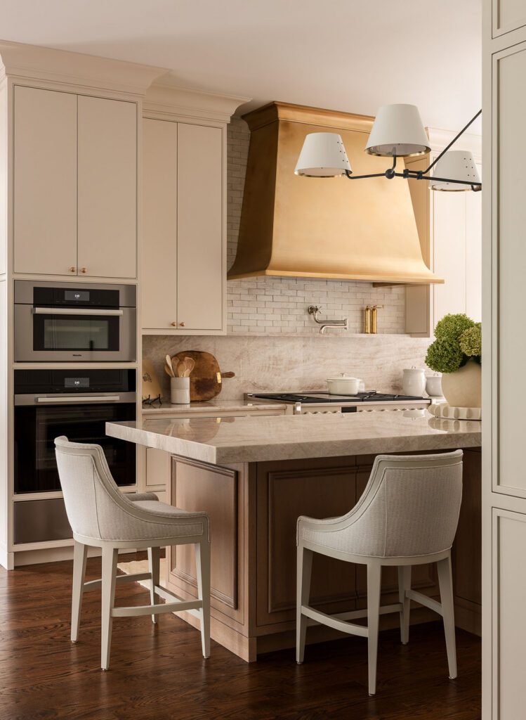 Westfield kitchen with island seating, built-in appliances, statement range hood, and light cabinetry