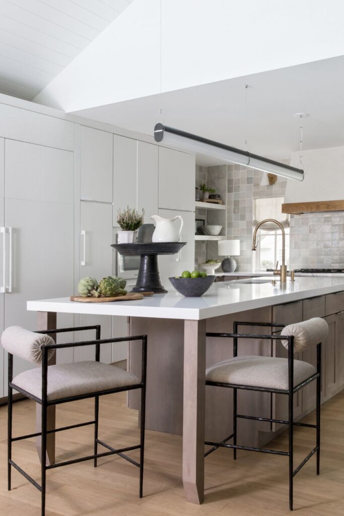 Cantilevered kitchen island with breakfast bar in a modern ranch home in Westfield, NJ featuring oak cabinetry, stone counters, and brass hardware.