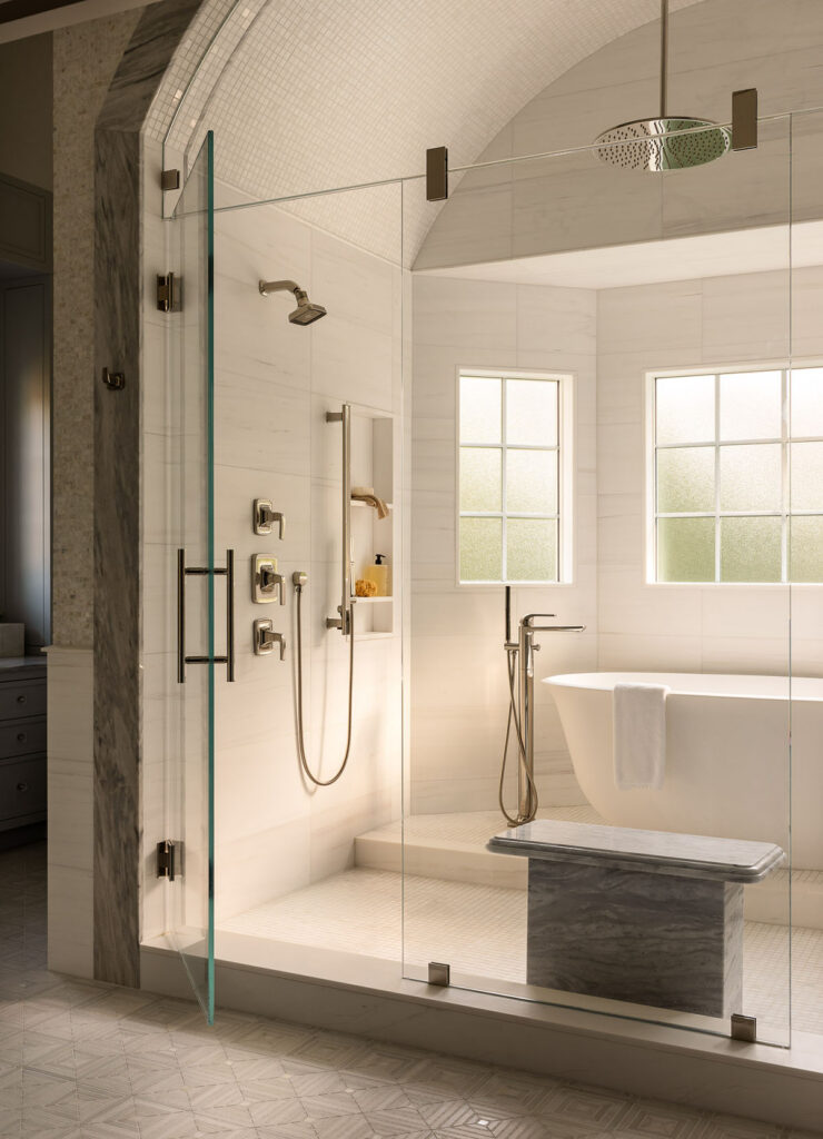 Luxury bathroom with walk-in shower, freestanding tub, glass enclosure, stone bench, and marble tile details