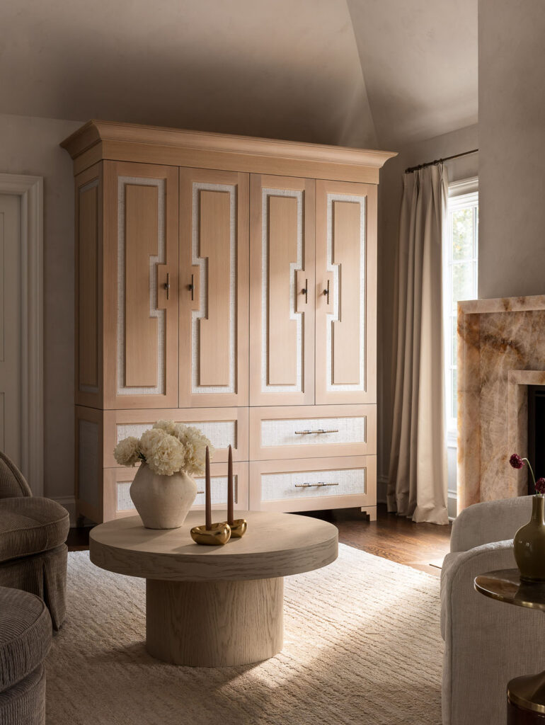 Luxury living room with custom built-in cabinetry, fireplace, round coffee table, and neutral upholstered seating