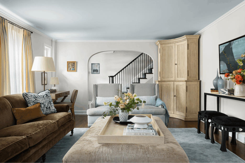 Living room in a Westfield NJ classic modern home with cozy textures, crown moldings, and a large arched doorway framing the staircase.