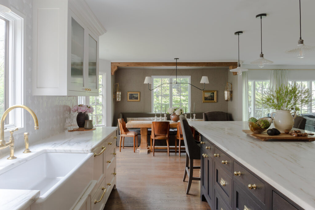 Full kitchen view showing the island, custom deep sink, hand-glazed tiles, breakfast nook and modern Tudor design.